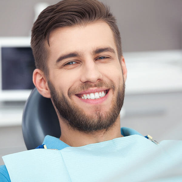A man at the dentist waiting for his metal-free fillings while smiling